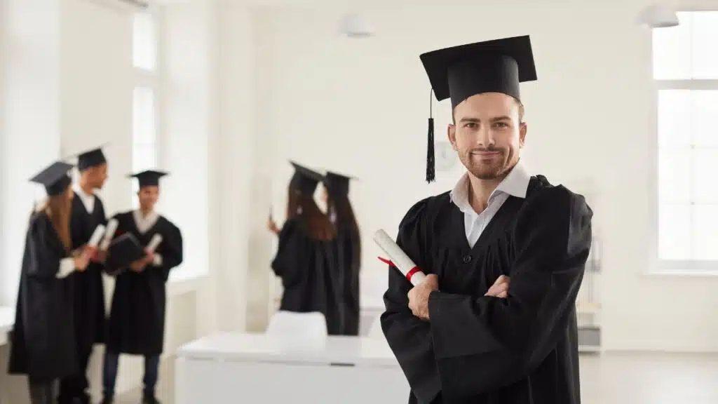 man holding his diploma cirficate looking at camera after completeing his graduation in academic regalia