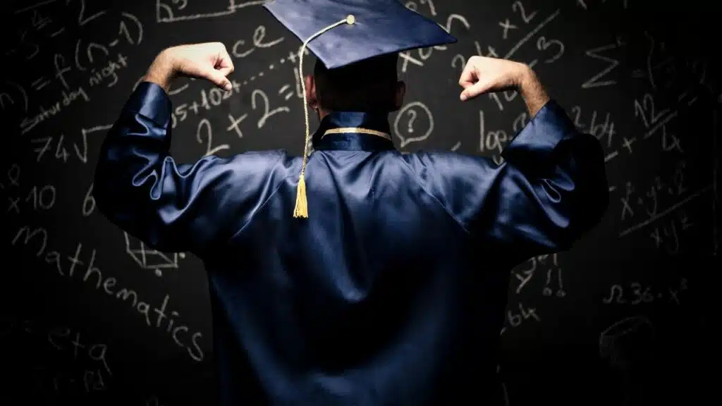 man posing in ifront of black board many number written on the board looks man completed his graduation and he is happy